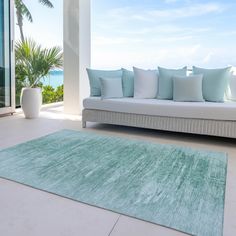 a white couch sitting on top of a floor next to a large blue area rug