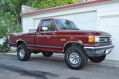 a red pick up truck parked in front of a garage