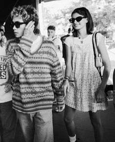 a group of people walking down a street next to each other with sunglasses on their faces