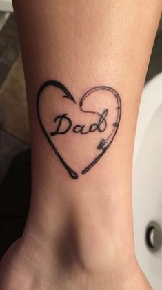 a tattoo that says dad on the side of a woman's foot with a heart and arrow