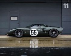 an old green race car parked in front of a garage door with the number 55 on it