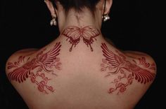 the back of a woman's neck with red tattoos on her upper and lower body