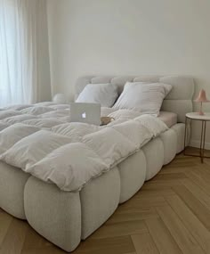 a bed that is made up with pillows and blankets on it, in front of a window