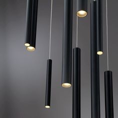 several black and white lights hanging from the ceiling in a room with grey walls,