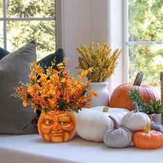 pumpkins, flowers and other decorative items sit on a window sill in front of a window