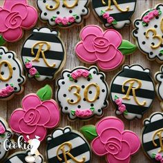 decorated cookies are arranged in the shape of roses and black and white with gold letters