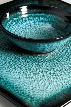 a blue bowl sitting on top of a green plate with a black rim and bottom