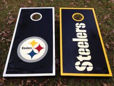 two cornhole game boards sitting on top of the grass with pittsburgh's logo painted on them