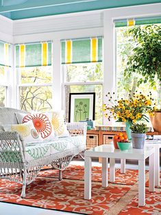 a living room with lots of windows and furniture on the floor, including a white wicker couch