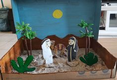 a cardboard box that has some kind of desert scene in it with palm trees and two people