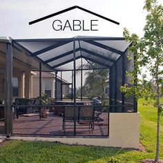 an enclosed patio with tables and chairs in the back ground, surrounded by grass and trees