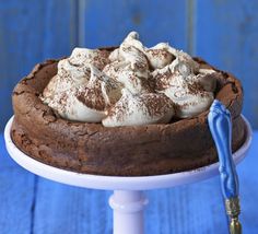 a chocolate cake with marshmallows on top is sitting on a white pedestal