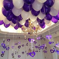 purple and white balloons are hanging from the ceiling