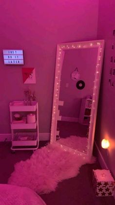 a pink room with a mirror and lights on the wall, next to a bed