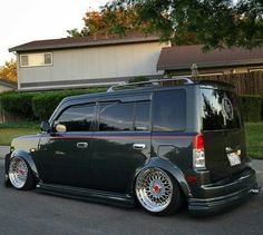 a black minivan parked in front of a house on the side of the road