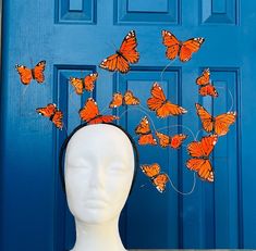 a white mannequin head with lots of orange butterflies on it's head