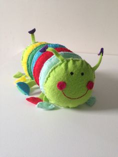 a small stuffed caterpillar sitting on top of a white table next to a wall