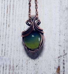 I handcrafted both the glass stone, and the wire wrap, right here in the USA.  The stone was made using premium glass color and an oxygen/propane torch.  I wrapped the stone in curvy copper wire for this one of a kind pendant that you will not find anywhere else.   The opalescence of this pendant is an enchanting phenomenon where light reveals a mesmerizing play of colors and hues. This delicate dance of iridescence creates a stunning visual effect, with shifting tones that range from deep emerald green to vibrant slyme yellow. The beauty of opalescence lies in its ability to capture and reflect light in a way that seems almost magical, adding depth and intrigue to everything it touches.  Designed for the connoisseur of fine jewelry, this exquisite piece features vibrant, opalescent hues t Handmade Oval Glass Necklace, Green Copper Hand Wrapped Necklaces, Green Hand Wrapped Copper Necklace, Glass Cabochon Pendant Jewelry, Fusion Wire Wrapped Necklace For Gift, Fusion Style Wire Wrapped Necklace For Gift, Bohemian Hand Wrapped Glass Jewelry, Artisan Wire Wrapped Czech Glass Necklaces, Green Wire Wrapped Glass Jewelry