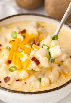 a bowl of potato soup with cheese and green onions