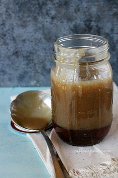 a spoon sitting next to a jar filled with liquid on top of a tablecloth