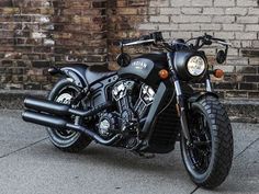 a black motorcycle parked in front of a brick wall