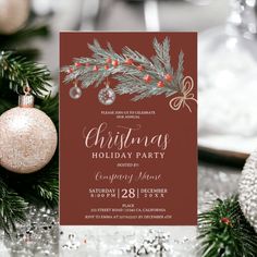 a christmas party card with ornaments and baubles on the table next to it