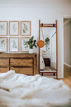 a bedroom with pictures on the wall and a dresser in front of it, along with a bed