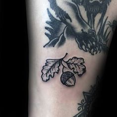 a close up of a person's leg with tattoos on it and an acorn