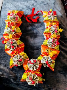 a necklace made out of candy wrappers on top of a black cloth covered bed