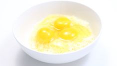 three eggs are in a white bowl on a white table top, with one egg missing