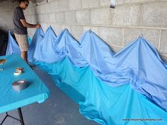 a man standing next to a table covered in blue tarps