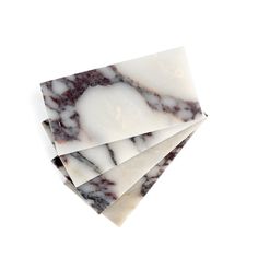 three pieces of white and brown marble sitting on top of each other in front of a white background