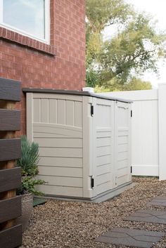 a white storage shed sitting next to a brick building