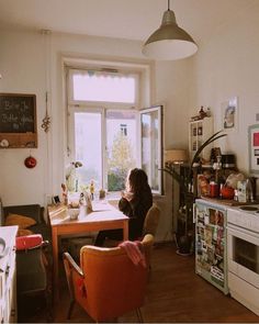 a woman sitting at a kitchen table in front of a window