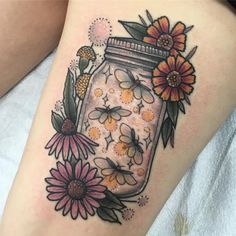 a woman's thigh with flowers and a mason jar tattoo on her leg,