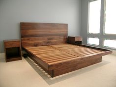 a bed with wooden headboard and foot board in a room next to two windows