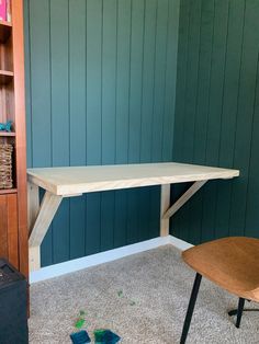 a wooden table sitting on top of a carpeted floor next to a book shelf