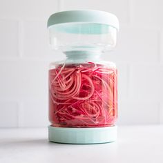 a jar filled with red onions sitting on top of a table