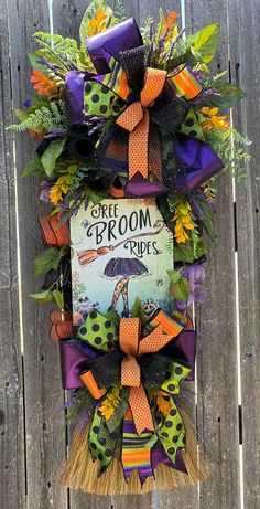 a halloween wreath hanging on the side of a wooden fence with an umbrella and book