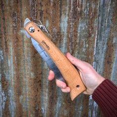 a person holding a knife in their left hand with rusted metal wall behind it