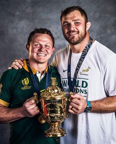 two men are posing for a photo with their trophy and the man is wearing a white t - shirt