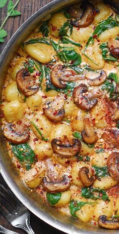 a pan filled with pasta and mushrooms on top of a wooden table