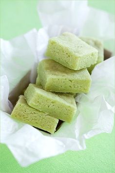 several pieces of green cake sitting in a white paper bag on a green tablecloth