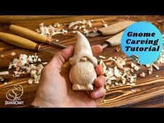 a hand holding a small mushroom in front of some wood shaving tools on a wooden table