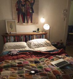 a laptop computer sitting on top of a bed next to a book shelf filled with books