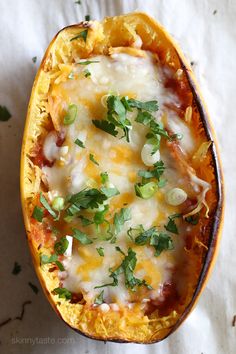 an overhead view of a stuffed squash with cheese and vegetables in it on a white surface