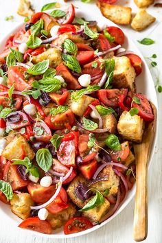 a white plate topped with tofu, tomatoes and onions next to some bread wedges