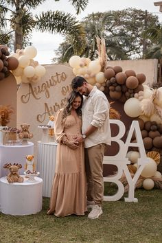 a man and woman standing next to each other in front of a baby shower sign