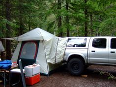 a white truck parked next to a tent in the woods