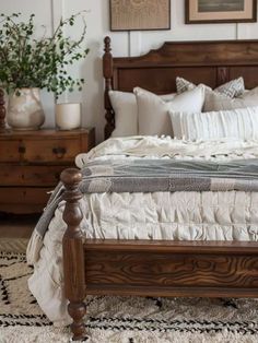 a wooden bed with white linens and pillows on top of it in a bedroom